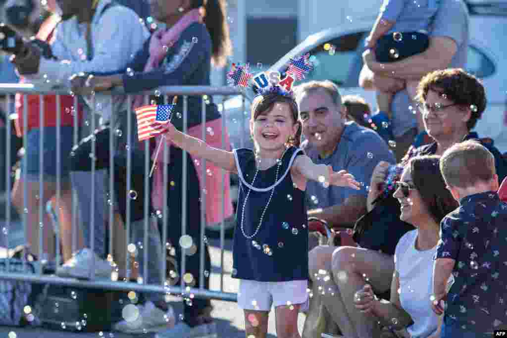 A child tries to capture bubbles in the air during the Fishtown Horrible's Parade, ahead of Independence Day, in Gloucester, Massachusetts, July 3, 2023.