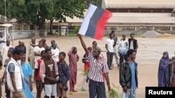 A man holds a Russian flag as Nigerians protest in the streets during anti-government demonstrations against bad governance and economic hardship, in Kaduna state, Aug. 5, 2024. 