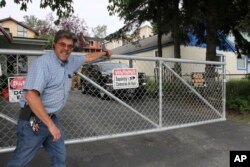 Danny Parish poses for a photo, July 26, 2023, as he closes the sliding gate he installed at his driveway across the street from Sullivan Arena in Anchorage, Alaska.