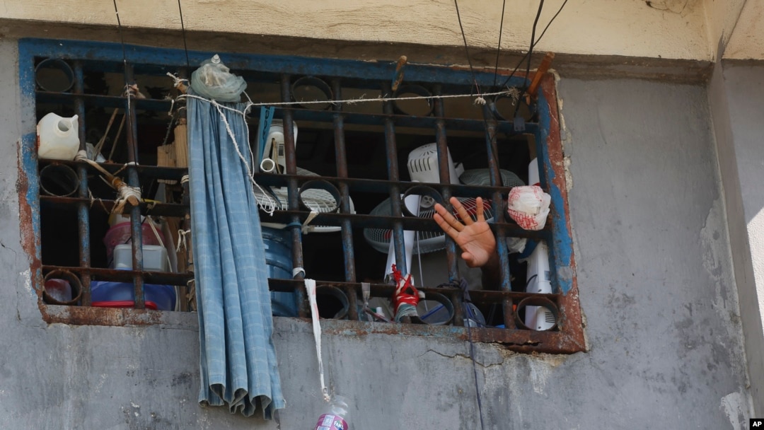 An inmate waves through a cell window at the National Penitentiary in Port-au-Prince, Haiti, Sunday, March 3, 2024. Thousands of inmates fled Haiti's main prison after armed gangs stormed the facility overnight.