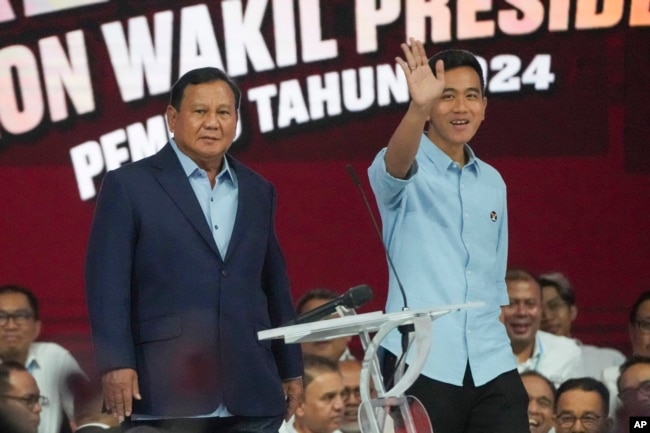 Capres Prabowo Subianto (kiri), bersama pasangannya Gibran Rakabuming Raka, dalam debat cawapres yang disiarkan televisi di Jakarta, Minggu, 21 Januari 2024. (AP/Tatan Syuflana)