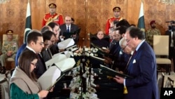 President Asif Ali Zardari, center left, administers the oath to ministers as Prime Minister Shehbaz Sharif, center right, watches during a ceremony at the Presidential Palace, in Islamabad, Pakistan, March 11, 2024, in this photo released by Pakistan's President Office. 