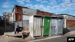 FILE - A man is sits on the pavement in Khayelitsha township, near Cape Town, April 21, 2022.