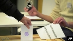 A woman casts her ballot at a polling station during presidential elections, in Helsinki, Finland, Jan. 28, 2024.