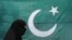 Seorang perempuan mengenakan burqa berjalan melewati bendera nasional Pakistan di Lahore 13 Agustus 2011. Pakistan mengatakan pada Rabu (17/1) bahwa Iran melakukan serangan udara di wilayahnya yang menewaskan dua anak. (Foto: REUTERS/Mohsin Raza)