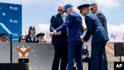 El presidente Joe Biden señala bolsas de arena después de caer en el escenario durante la ceremonia de graduación de la Academia de la Fuerza Aérea de EEUU el 1 de junio de 2023, en la Academia de la Fuerza Aérea en Colorado Springs, Colorado.