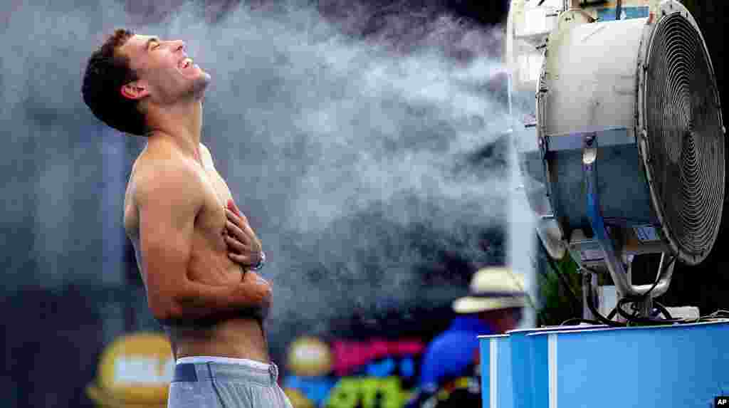 Poland&#39;s Jerry Janowicz is sprayed with cool water at the Australian Open tennis championship in Melbourne. The Australian Open organizers implemented the Extreme Heat Policy when the temperature topped 43&deg;C (109&deg;F) and play was halted for just over fours on the outside courts but continued on the covered show courts.