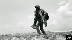 Một binh sĩ Thủy quân lục chiến miền Nam Việt Nam mang thi thể đồng đội tử trận đi trên Quốc Lộ 1, tỉnh Quảng Trị, ngày 30/4/1972. Hiện có khoảng nửa triệu người Việt thiệt mạng trong chiến tranh mà chưa được xác định.