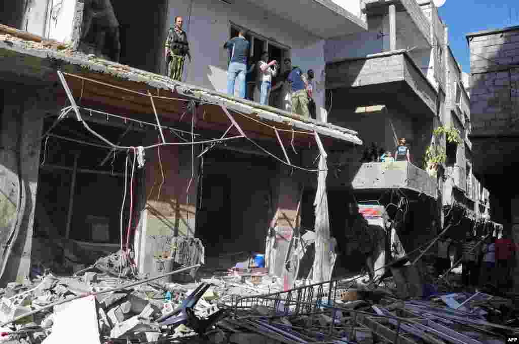 Syrian citizens and security forces inspecting the sight of a car bomb attack in Damascus&#39; Tadamun neighborhood.