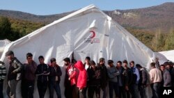 Migrants wait in line to receive supplies from the Red Cross at the Vucjak refugee camp, outside Bihac, in northwestern Bosnia, Oct. 21, 2019.