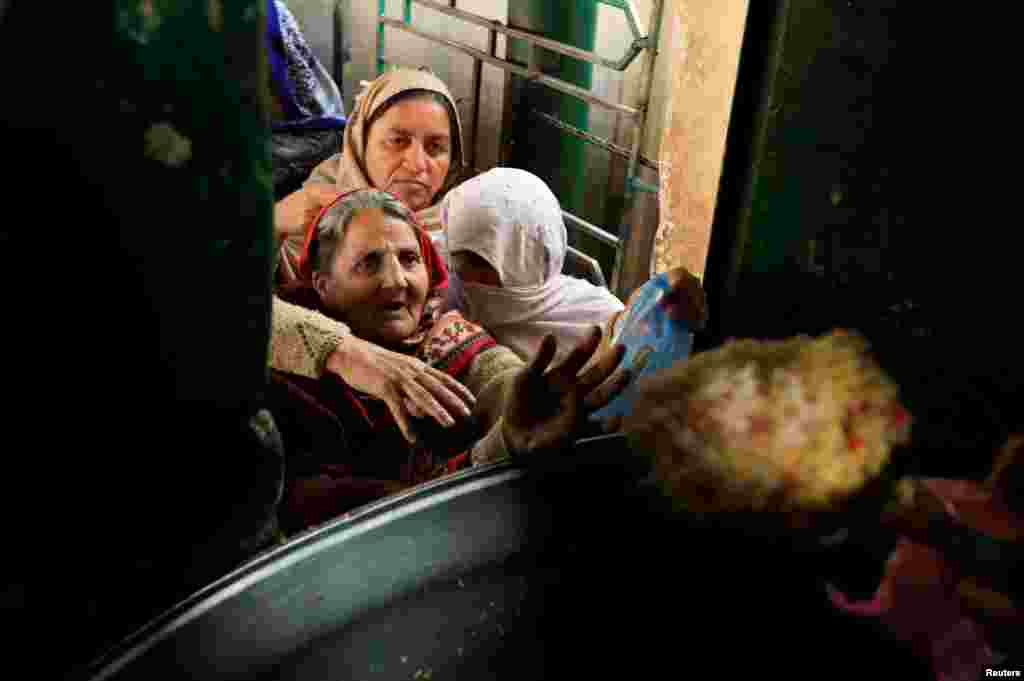 Women receive free food at a distribution center at the Bari Imam Shrine in Islamabad, Pakistan.