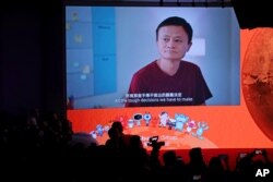 FILE - A screen shows footage of Alibaba Group co-founder Jack Ma during the Alibaba Group's listing ceremony at the Hong Kong Stock Exchange (HKEX) in Hong Kong, Nov. 26, 2019.
