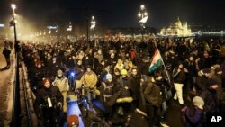 Anti-government demonstrators march across Margaret Bridge over the River Danube with the Parliament building in the background, in Budapest, Hungary, Dec. 16, 2018.