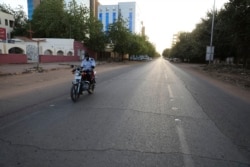 FILE - A lone motorcyclist is seen on an otherwise empty street in Khartoum, Sudan, March 24, 2020, as the Sudanese government ordered a nighttime curfew to prevent the spread of the coronavirus.