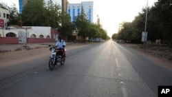 FILE - A lone motorcyclist is seen on an otherwise empty street in Khartoum , Sudan, March 24, 2020, as the Sudanese government ordered a nighttime curfew to prevent the spread of the coronavirus.