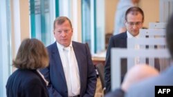 Senior public prosecutor Jasper Klinge (2ndL) and State prosecutor Philipp Boegner (R) stand in the courtroom prior to the start of a trial against two Syrian defendants accused of state-sponsored torture in Syria, April 23, 2020 in Koblenz, Germany. 