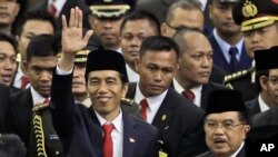 Indonesian President Joko Widodo, center, waves as he walks with his deputy Jusuf Kalla, bottom right with glasses, after their inauguration ceremony at the Parliament building in Jakarta, Indonesia, Monday, Oct. 20, 2014.
