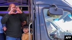 The sister of late Israeli hostage Shiri Bibas, Dana Silberman-Sitton, sits in the front of a vehicle while other family members greet mourners awaiting the Bibas funeral convoy in kibbutz Nir Oz in southern Israel, Feb. 26, 2025.