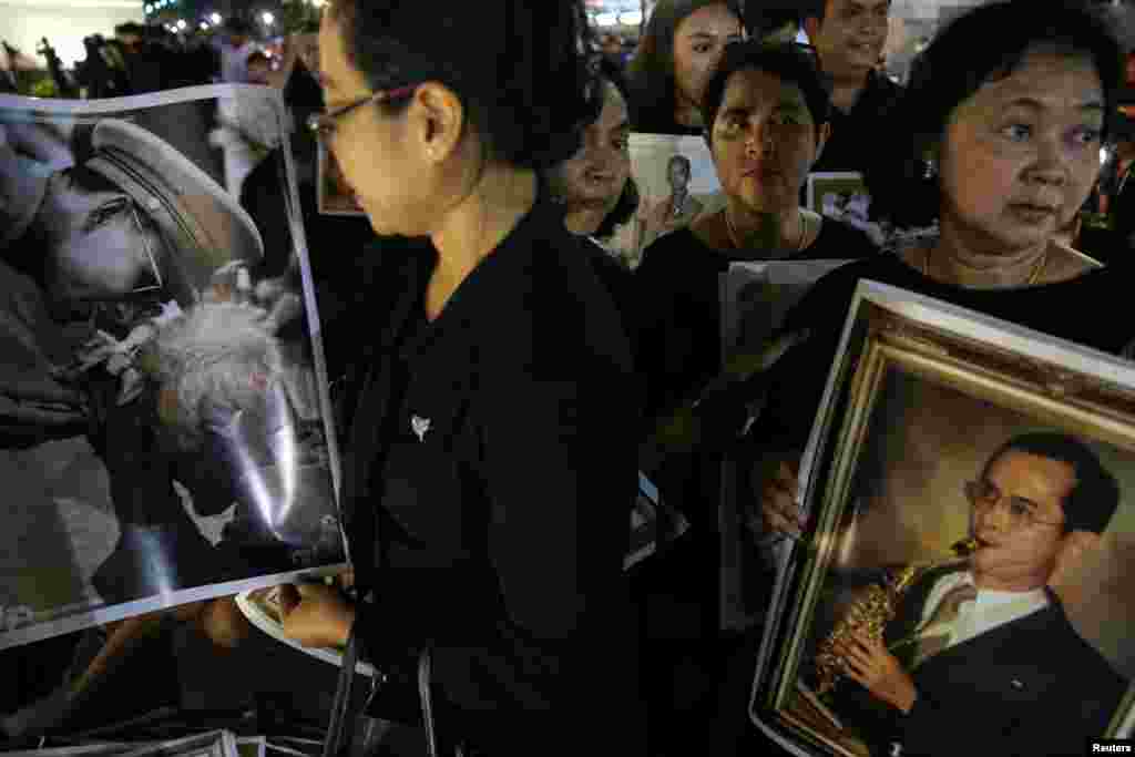 Warga membawa foto-foto mendiang Raja Bhumibol Adulyadej di hari terakhir masyarakat umum diperbolehkan memberikan penghormatan terakhir di ruang tahta di Bangkok, Thailand, 5 Oktober 2017. &nbsp;