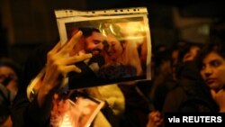 A woman holds a picture of newlyweds, victims of the crash of a Ukraine International Airlines plane, as people gather to show their sympathy in Tehran, Iran, Jan. 11, 2020. 