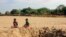 FILE —Children sit by a dug out water hole in a dry river bed in the remote village of Fenoaivo, Madagascar, November 11, 2020. The group World Weather Attributions blames climate change for a heatwave in October 2023.