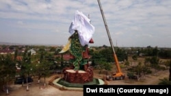 Workers cover at the statue in Tuban, East Java, of the Chinese warrior god known variously as Kwan Sing Tee Koen, Kwan Kong, Kuan-Ti or Guan-Yu.