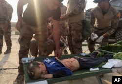 Soldiers give the first aid to a boy injured during the clashes between Iraq's elite counterterrorism forces and Islamic State militiants in the village of Tob Zawa, about 9 kilometers (5½ miles) from Mosul, Iraq, Oct. 25, 2016.