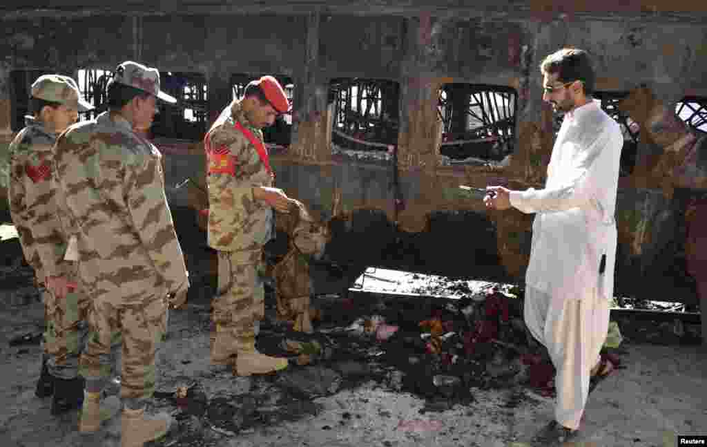 Security officials collect evidence near a damaged passenger carriage at the site of a bomb blast in the town of Sibi, Pakistan, April 8, 2014.