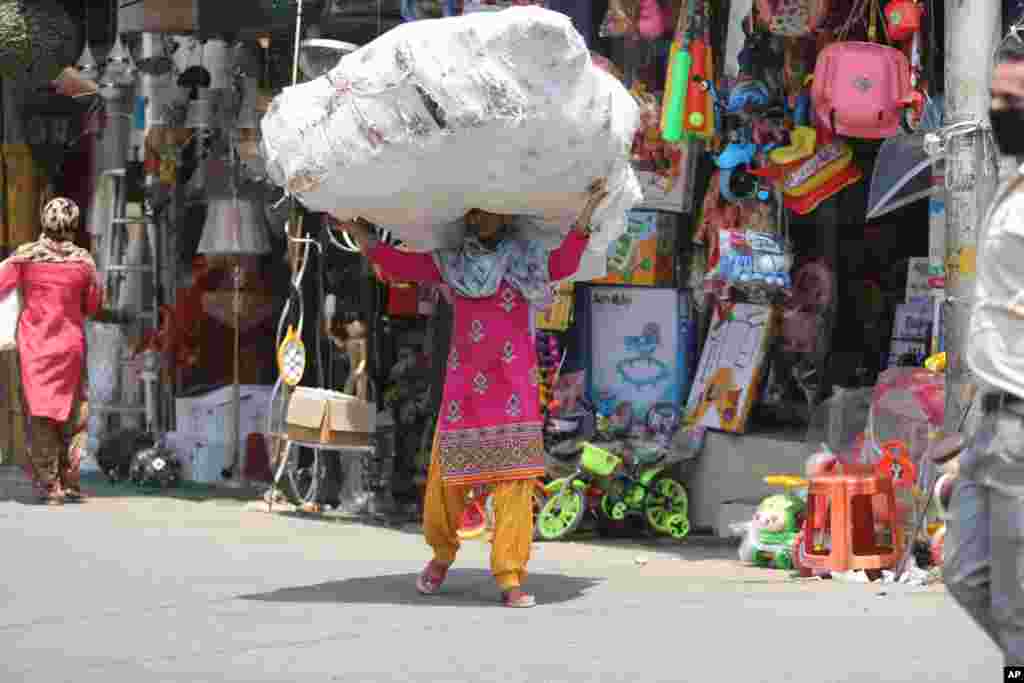 A laborer carries a load of plastic toys at a market in Jammu, India. 