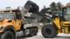 FILE - Maryland Department of Transportation employees use a backhoe to load a truck with salt in LaVale, Md., Feb. 5, 2025.