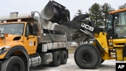 FILE - Maryland Department of Transportation employees use a backhoe to load a truck with salt in LaVale, Md., Feb. 5, 2025.