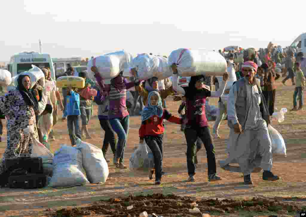 Syrian refugees walk at the border in Suruc, Turkey, Sept. 20, 2014.