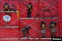 Members of the Fullpaint 360 collective paint a mural titled "Outside" designed by Salvadoran artist Fernando Orellana, in Mejicanos, El Salvador, July 2, 2024.