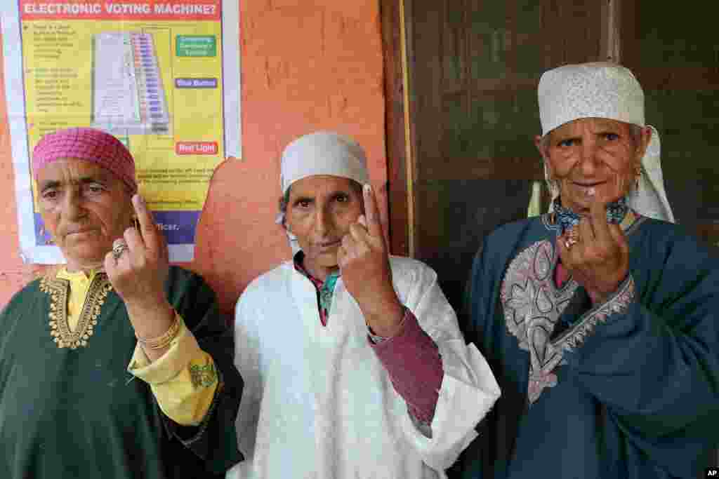 Kashmiri women display the indelible ink mark on their fingers after casting their votes in Sheeri, about 60 kilometers north of Srinagar, India, May 7, 2014.