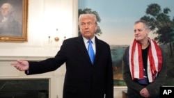 President Donald Trump, accompanied by Marc Fogel, speaks in the Diplomatic Reception Room at the White House, Feb. 11, 2025, in Washington.