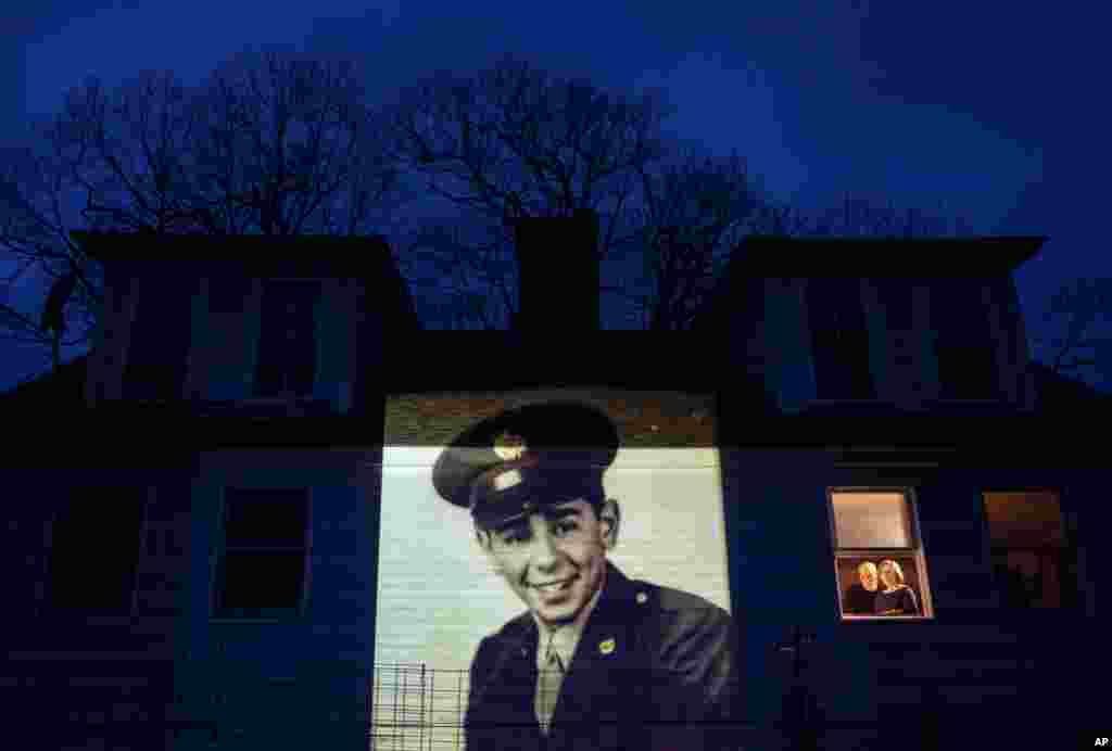 Изображение ветерана Второй мировой войны Эмилио ДиПальмы проецируется на дом его дочери Эмили Ахо в Джаффри, Нью-Хэмпшир. ДиПальма умер от COVID-19 в возрасте 93 лет (фото: AP/David Goldman)