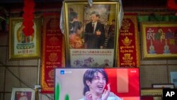 A television shows a broadcast of a Chinese talk show program as it sits beneath a photo of Chinese President Xi Jinping in a home converted into a tourist homestay in Zhaxigang village near Nyingchi in western China's Tibet Autonomous Region. (AP Photo/Mark Schiefelbein, File)