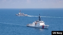 美国海军公布的图片显示美国海军“基德”号阿利·伯克级导弹驱逐舰与美国海岸警卫队“蒙罗”号传奇级巡逻舰在当地时间2021年8月27日例行穿越台湾海峡的国际水域。