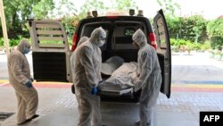 Des employés transportent le corps d'une victime du COVID-19 qui sera incinérée au crématorium hindou New Sonapur dans l'émirat du Golfe de Dubaï le 19 avril 2020. (Photo: GIUSEPPE CACACE / AFP)