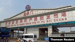 一警察面帶口罩站在北京新發地農產品批發市場入口處。該市場因發現新形冠狀病毒感染被關閉。