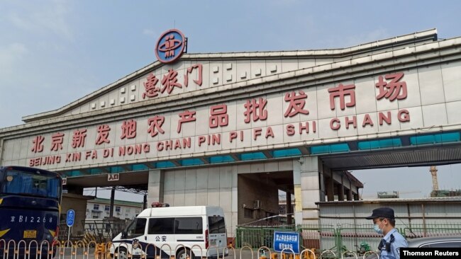 一警察面带口罩站在北京新发地农产品批发市场入口处。该市场因发现新形冠状病毒感染被关闭。