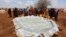 Internally displaced Somali women gather to collect water from a plastic pan after fleeing from drought stricken regions near a makeshift camp in Baidoa, west of Somalia's capital Mogadishu, March 26, 2017. 