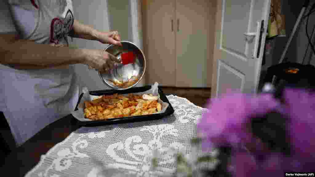 Jelena Petrovic prepares food in her home and puts it in the oven.