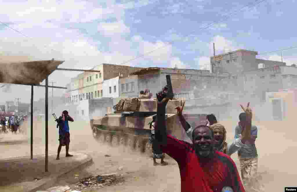 Southern Popular Resistance fighters react as one of their tanks fire at a Houthi position during fighting in Yemen's southern city of Aden.