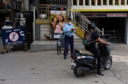 A policeman takes notes as he asks a motorist about his reasons for being out during a curfew imposed to curb the spread of the coronavirus in Dharmsala, India, May 15, 2021.