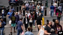 Masked and unmasked pedestrians walk along the Las Vegas Strip, April 27, 2021, in Las Vegas, Nevada.