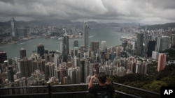 FILE - A visitor sets up his camera in the Victoria Peak area to photograph Hong Kong's skyline, Sept. 1, 2019. 