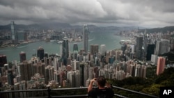 资料照片：一名游客在维多利亚山顶地区架起相机，拍摄香港的天际线。(2019年9月1日)