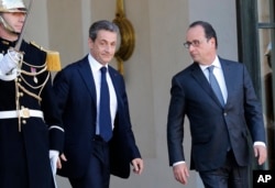 Former French President, Nicolas Sarkozy, leaves the Elysee Palace after a meeting with France's President, Francois Hollande, right, in Paris, Sunday, Nov. 15, 2015.