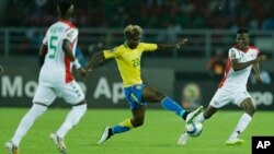 Le Gabonais, Didier Ibrahim Ndong, centre, tente un drible face à Jonathan Zongo du Burkina Faso, à droite, lors du match de la Coupe d'Afrique des Nations entre le Burkina Faso et le Gabon à Bata, Guinée équatoriale, 17 janvier 2015. 